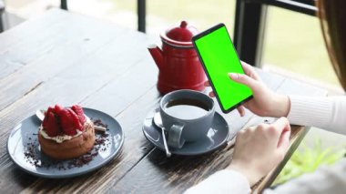 Bir kafede yeşil ekranda akıllı telefon, krom anahtar yeşil ekranlı akıllı telefon, yeni teknoloji kavramı kapanıyor.
