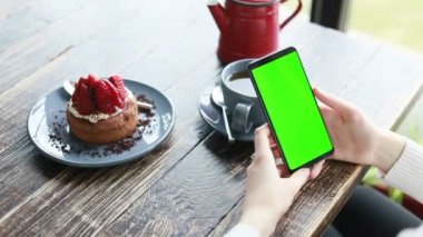 Bir kafede yeşil ekranda akıllı telefon, krom anahtar yeşil ekranlı akıllı telefon, yeni teknoloji kavramı kapanıyor.