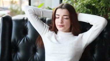 Rahat bir kanepede dinlenen ve hayal kuran mutlu genç bir kadın. Rahatlamış milenyum kızı başka tarafa bakıyor, gülümsüyor, evinde dinleniyor. Huzurlu bayan rüya görüyor, stres yok.