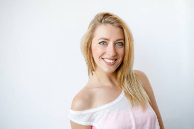 Güzel, neşeli, sarışın bir kadın, kameraya bakarak, mutlu. Güzel bir kadının stüdyo resmi. Boş bir stüdyo duvarında izole edilmiş..