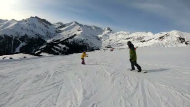 Güneşli havada dağlarda snowboard yapmak. Bir adamın dağdan kayarak inmesi ve numaralar yapması..