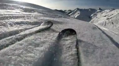 Güneşli havada dağlarda snowboard yapmak. Bir adamın dağdan kayarak inmesi ve numaralar yapması..