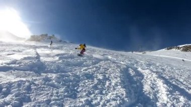 Güneşli havada dağlarda snowboard yapmak. Bir adamın dağdan kayarak inmesi ve numaralar yapması..