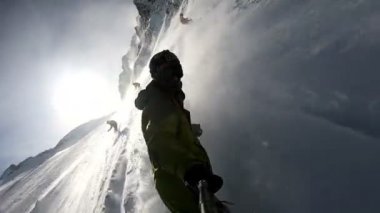 Neşeli snowboardcular güneşli kış günlerinde karlı dağlarda snowboard yaparken eğleniyorlar. Aşırı serbest gezen snowboardcular taze toz kar sürüyor ve piste toz yapıyor.