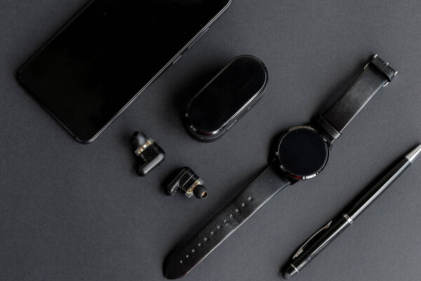 Аксессуары для мужской красоты на монохромном фоне. черная ручка, черные умные часы, смартфон и беспроводные наушники на темном фоне. Вид сверху. Минималистский чёрный тренд 2020
.