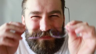 Beyaz tişörtlü adam gözlük takıyor, portre yapıyor. Gözlüksüz yakışıklı genç adam kötü görüyor. Zayıf görme konsepti.