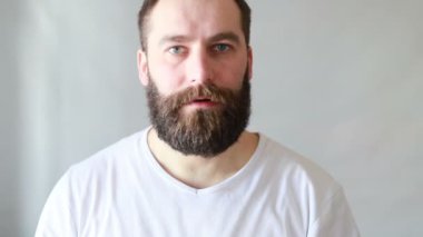 Avrupalı yakışıklı adam parmaklarını gri arka planda tutuyor. Şşş, sır, sessizlik jesti.