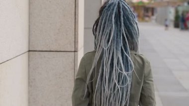 Rastalı genç, güzel, gülümseyen bir kadının portresini yakından çek, neşeyle şehirde yürüyen kameraya bak.