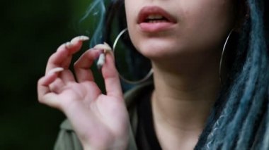 Sunset, Close Up 'ta esrar içen kadın. Kadın esrarı taze marihuana otundan sardı, marihuana içme kavramları. Hafif uyuşturucu kullanan kadın esrar içiyor. Rastalı kadın..