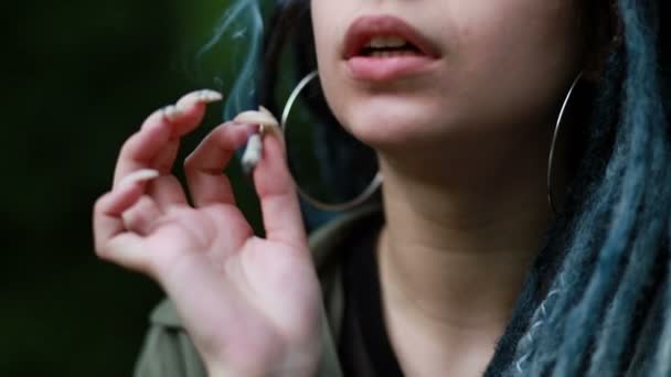 妇女在日落时吸食大麻 那个女人把大麻从新鲜的大麻杂草 吸食大麻的概念上卷了起来 轻毒女人抽大麻 有可怕头发的女人 — 图库视频影像