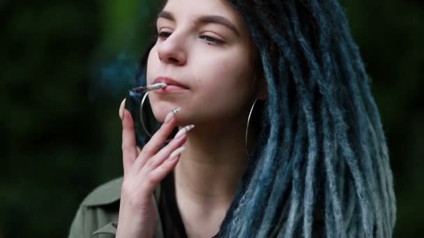 妇女在日落时吸食大麻 那个女人把大麻从新鲜的大麻杂草 吸食大麻的概念上卷了起来 轻毒女人抽大麻 有可怕头发的女人 — 图库视频影像