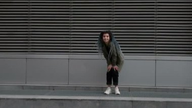 Sokakta dans eden, rastaları sallayan mavi saçlı çekici kız. Rastalı kadın sokakta dikiliyor. Kız saçı rüzgarda dalgalanıyor..