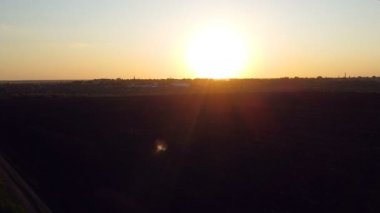 Tarım kıtlığı üzerinde gün batımı. Hava fotoğrafçılığı: kırsal alan, yeşil çayır ve sürülmüş siyah tarla, kamera tarlanın ve yeryüzünün sınırında uçuyor, ilkbaharda gün batımında,.