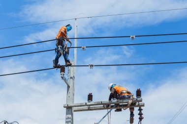 Elektrikçiler Kablo Tamir Servisi, vinç kamyonunda çalışan işçiler yüksek voltaj iletim hattını tamir ediyor, elektrik direğinin elektrik hattını kuruyorlar..