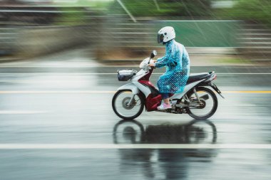 Motosiklet yağmurluğunda, yağmurda insanlar yağmurda motosiklet kullanır. Hareket bulanıklığı, koşma basamağında bulanıklık..;