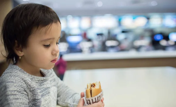 Cute girl eating a hamburger in the Fast food — Stock Photo, Image