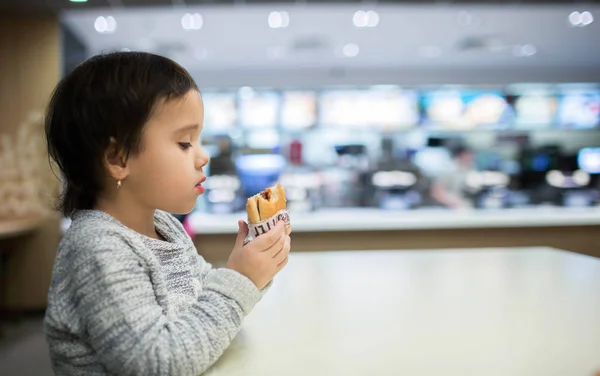 Cute girl eating a hamburger in the Fast food — Stock Photo, Image