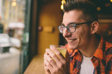 Genç öğrenci restoranda oturuyor ve sıcak bir içecek tadıyor. Kafede çay içen adam.