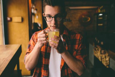 Genç öğrenci restoranda oturuyor ve sıcak bir içecek tadıyor. Kafede çay içen adam.