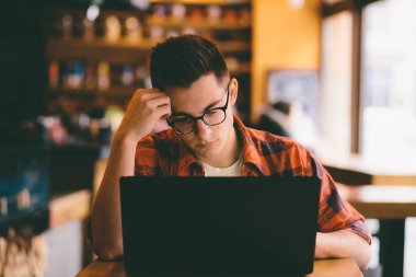 Kafede dizüstü bilgisayar kullanan mutlu casual adam.