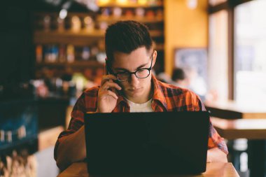 Smartphone ve dizüstü bilgisayar kullanan mutlu casual adam