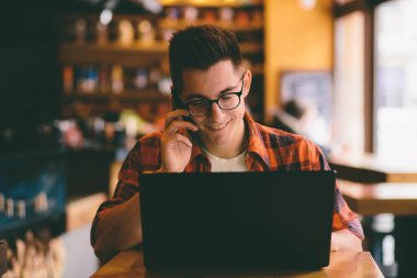 Smartphone ve dizüstü bilgisayar kullanan mutlu casual adam