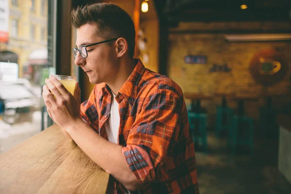 Jeune étudiant est assis dans le restaurant et déguster une boisson chaude. homme buvant du thé au café — Photo