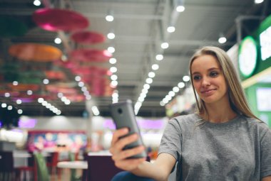 Restoran terasında, odaklanmamış bir geçmişi olan akıllı bir telefonla mesajlaşan kız.