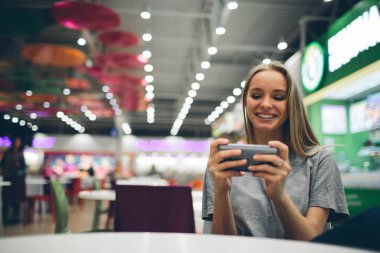 Restoran terasında, odaklanmamış bir geçmişi olan akıllı bir telefonla mesajlaşan kız.