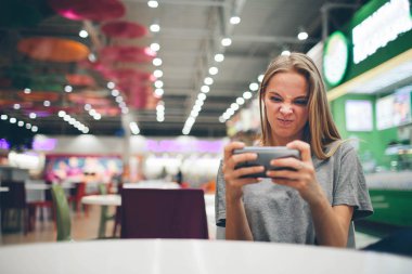 Restoran terasında, odaklanmamış bir geçmişi olan akıllı bir telefonla mesajlaşan kız.