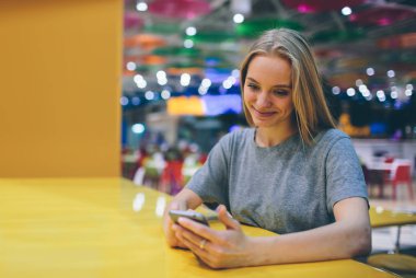 Restoran terasında, odaklanmamış bir geçmişi olan akıllı bir telefonla mesajlaşan kız.