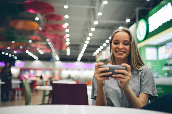 Egy lány sms-ezik az okostelefonon egy étterem teraszán, koncentrálatlan háttérrel — Stock Fotó