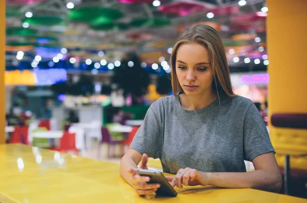 Girl texting on the smart phone in a restaurant terrace with an unfocused background — Stock Photo, Image