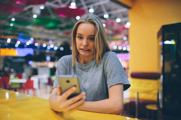 在一个没有聚焦背景的餐厅平台上用智能手机发短信的女孩 — 图库照片