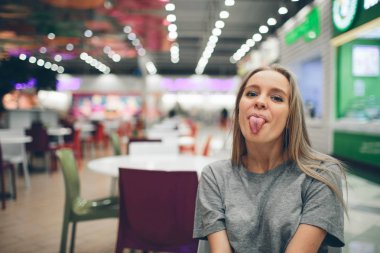 Yemek salonunda dil gösteren genç ve güzel bir kızın portresi. Odaklanmamış bir geçmişi var.