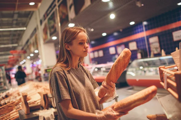 Jovem escolhe pão na loja — Fotografia de Stock