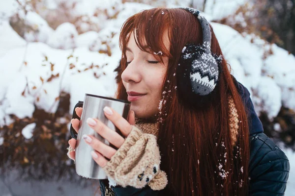 Téli. Fül muffok visel vörös hajú nő. Lány iszik forró tea vagy kávé vas hőtartó Varázsitató — Stock Fotó