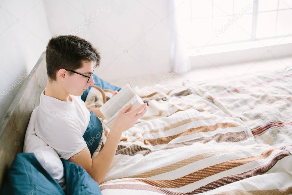 Man reading a book on his bed at home