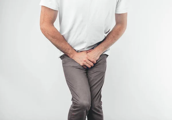 A man holding his penis with on the white background. Wants to go to the toilet. — Stock fotografie