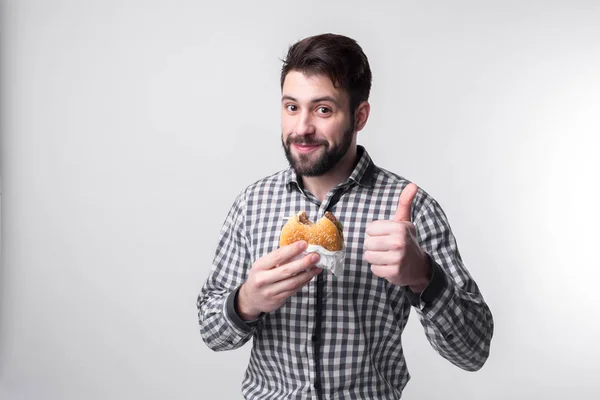 Man houdt een stuk van de hamburger. student eet fast-food. niet nuttig voedsel. zeer hongerig kerel — Stockfoto