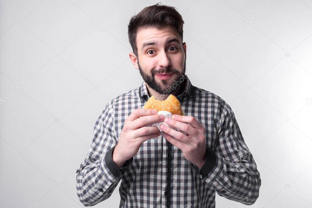man holding a piece of hamburger. student eats fast food. not helpful food. very hungry guy