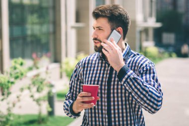 Yakışıklı sportif kahve içme ve telefonda konuşurken esmer adam sakallı