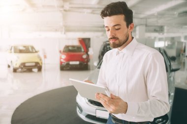 yeni showroom arabalara sunmak kolay araç satıcısı. Genç erkek danışman gösteren yeni araba auto show fotoğraf. Kiralık Araba konsepti