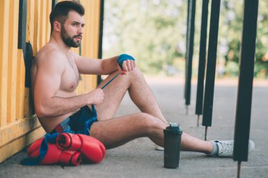 adam boks bandaj oturur asfalt üzerinde çeker. Eşcinsel spor içinde fikir tartışması için hazırlanıyor. Boks halka açık havada. Açık havada mücadele