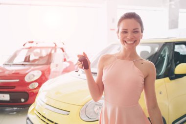 Kadını sürücüsü Holding arabanın anahtarları. Araç edilmesidir. Satıcı veya araba satıcısı ve erkek müşteri veya müşteri araba bayilik yeni ve kullanılmış araba showroom ve eller iç dekorasyonunu sunma içinde