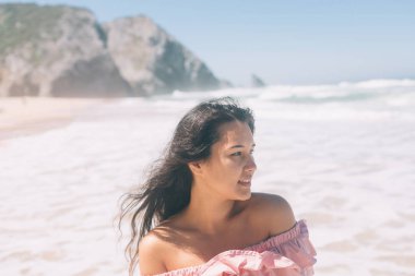 okyanus kıyısında bir hafif pembe elbiseli kadın