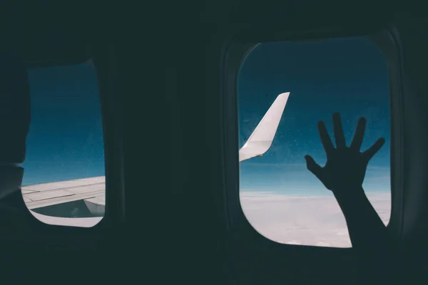 Young girl looking through window in airplane