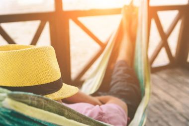 Güneşli bir plaj bir okyanus tarafından adlı bir hamakta yatan yakışıklı genç adam