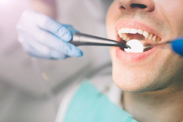 Retrato de un dentista que trata los dientes de un paciente joven . — Foto de Stock