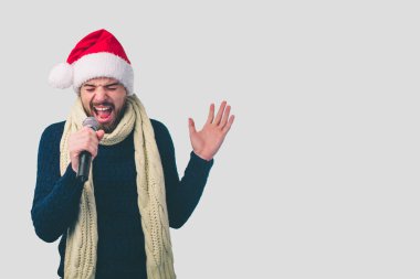 Çocuk bir Noel şapka sallanan dışarı. Işık izole mikrofon şarkı yakışıklı bir adam görüntüsü. Duygusal portre gri bir arka plan üzerinde çekici bir adam. İnek gözlük takıyor.